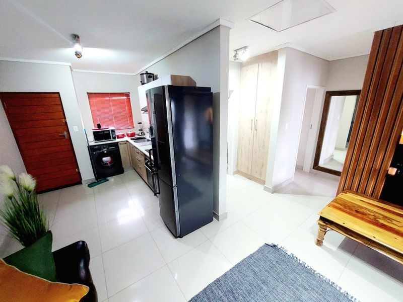Open plan living area featuring tiled flooring, built-in kitchen cabinetry, and integrated storage cupboards in a well-maintained modern layout.