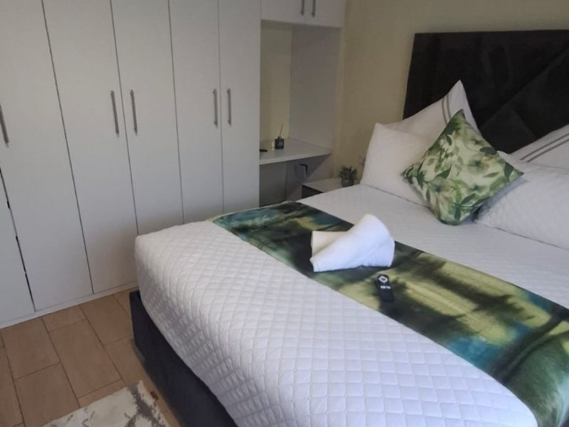 A well-maintained bedroom featuring extensive built-in white cabinetry and modern laminate flooring.