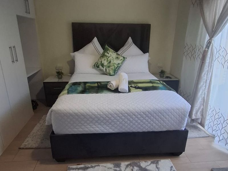 A well-maintained bedroom featuring tiled flooring, built-in cupboards, and a sliding door providing natural light.