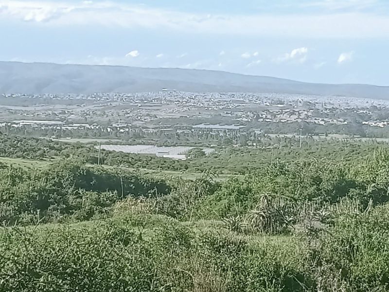 A panoramic landscape view overlooking a valley with distant residential development and natural vegetation.