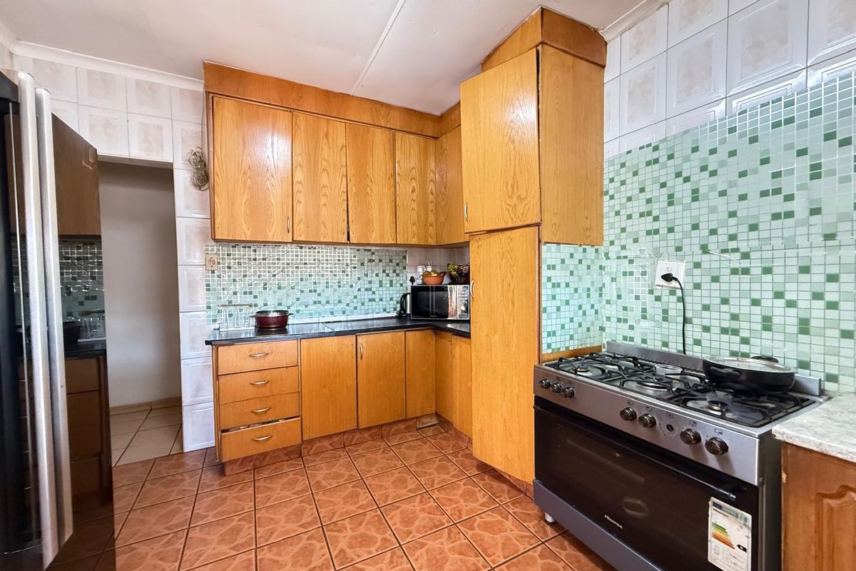 A functional kitchen featuring wooden cabinetry, tiled splashbacks, and a freestanding gas stove with oven.