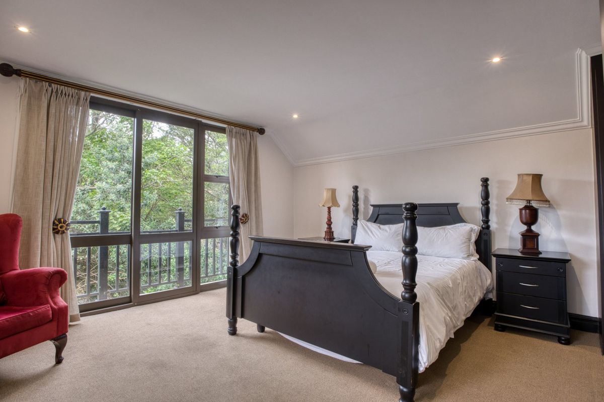 Spacious bedroom featuring large sliding glass doors that open to a private balcony with lush green views and recessed ceiling lighting.