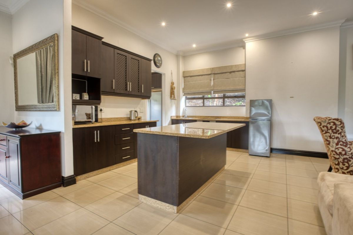 A well-maintained kitchen featuring dark wood cabinetry, granite countertops, a central island, and tiled flooring, offering a functional and clean cooking space.