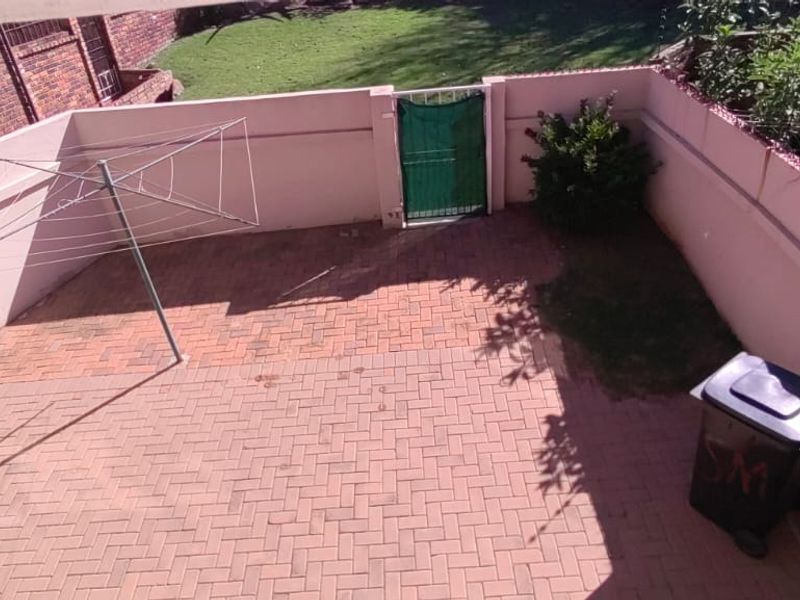 A private rear courtyard featuring paved flooring, a perimeter wall, and a metal gate, providing a functional outdoor space.