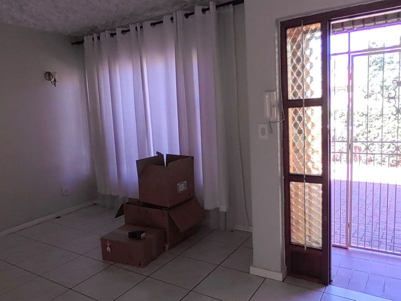 An entry area featuring tiled flooring, a security gate, and an intercom system, providing direct access to the exterior patio.