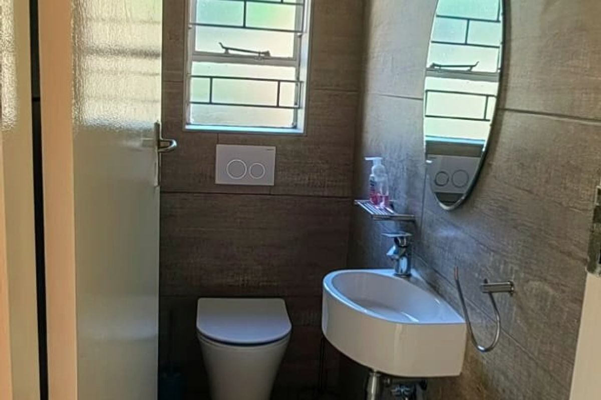 A compact, modern guest bathroom featuring wood-look floor and wall tiles, a wall-mounted basin, and a wall-hung toilet.