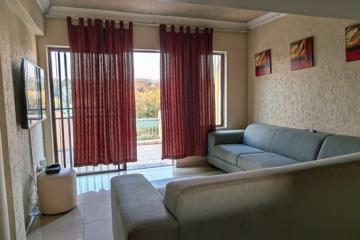 A living room featuring tiled floors, textured walls, and a sliding glass door providing access to an outdoor balcony area.