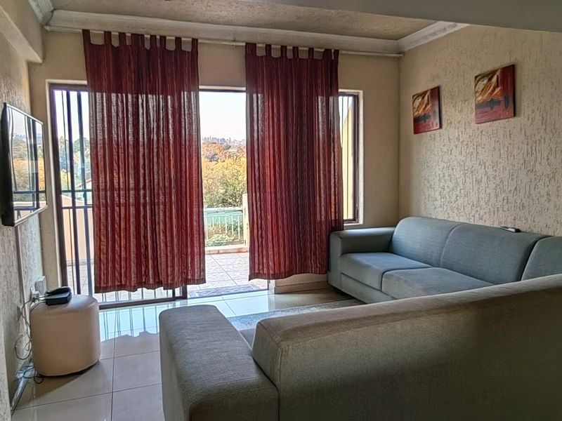 A living room featuring tiled floors, textured walls, and a sliding glass door providing access to an outdoor balcony area.