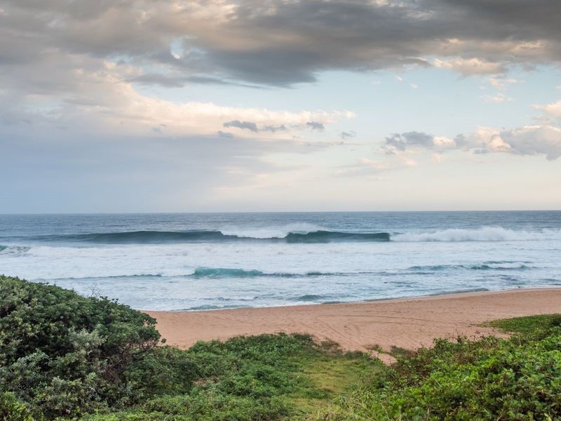 A scenic view of the ocean and sandy beach, showcasing the natural coastal landscape of the property.