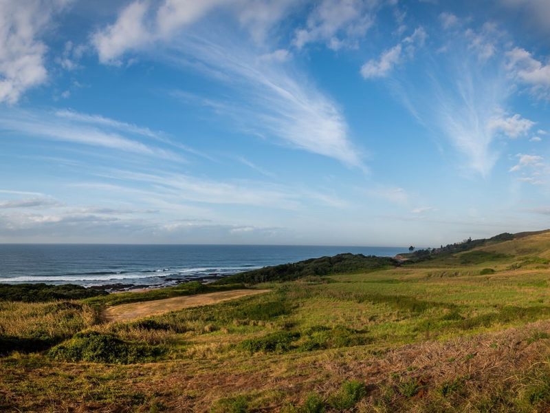 A panoramic view of the coastal landscape featuring rolling green hills and direct ocean frontage.