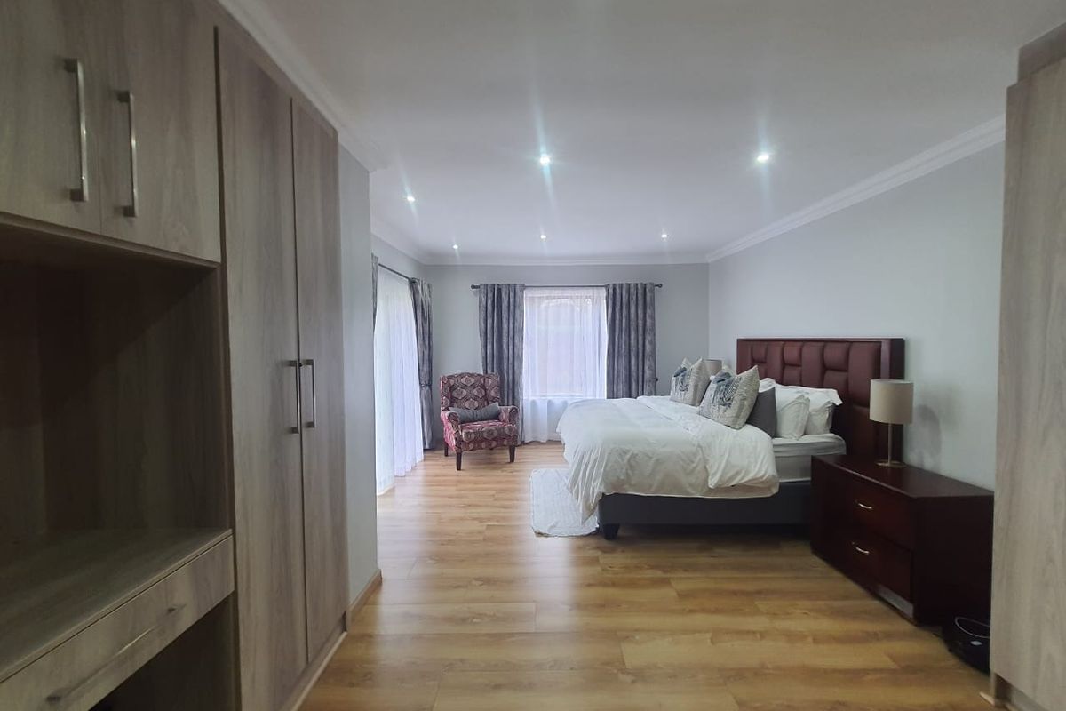 Spacious bedroom featuring wood-look flooring, recessed ceiling lighting, and extensive built-in cabinetry with a dedicated vanity area.