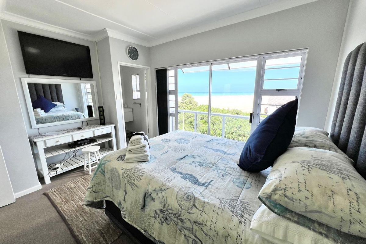 A bright bedroom featuring large sliding glass doors that open to a balcony with scenic ocean views.