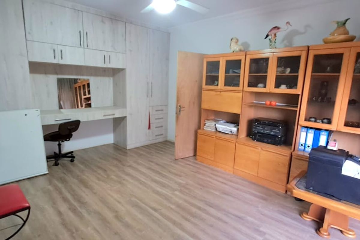 A bedroom featuring extensive built-in cabinetry with a integrated vanity desk and light wood-look laminate flooring.