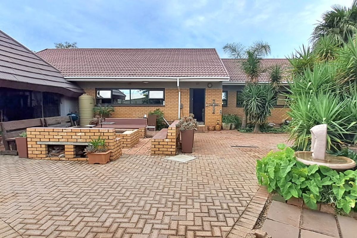 A spacious rear courtyard featuring brick paving, a built-in brick seating area, and established garden landscaping.