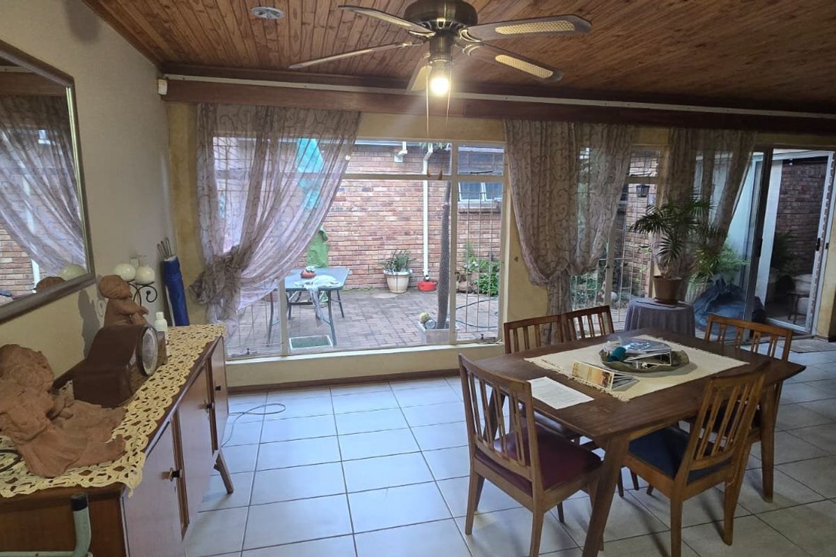 Spacious living area featuring a timber-clad ceiling, ceiling fan, and large sliding glass doors that open onto a private brick-paved patio.