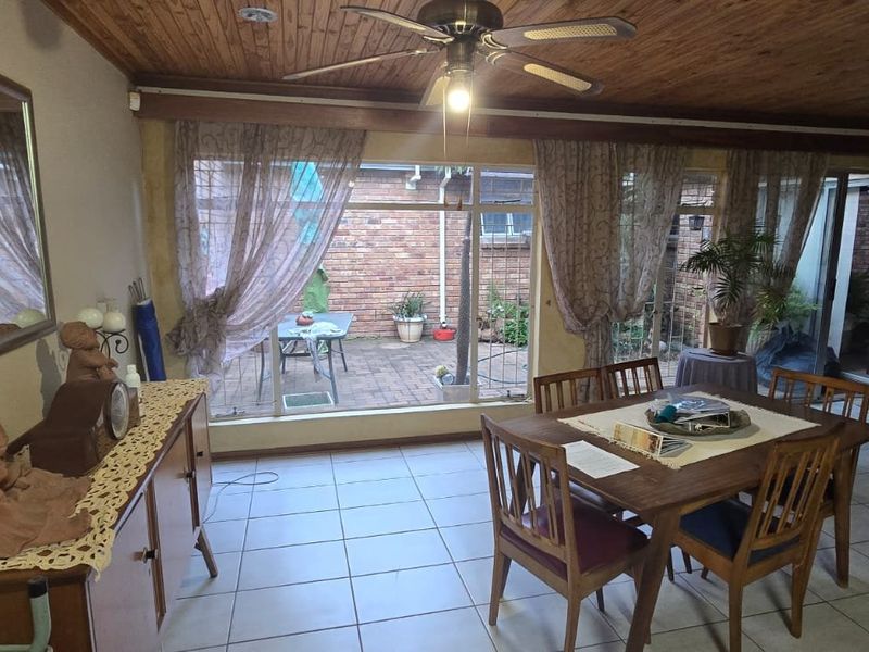 Spacious living area featuring a timber-clad ceiling, ceiling fan, and large sliding glass doors that open onto a private brick-paved patio.