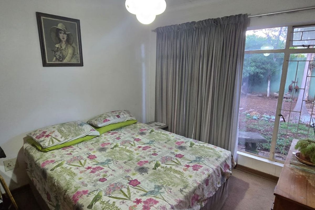 A bedroom featuring a large window with garden views and neutral wall finishes.