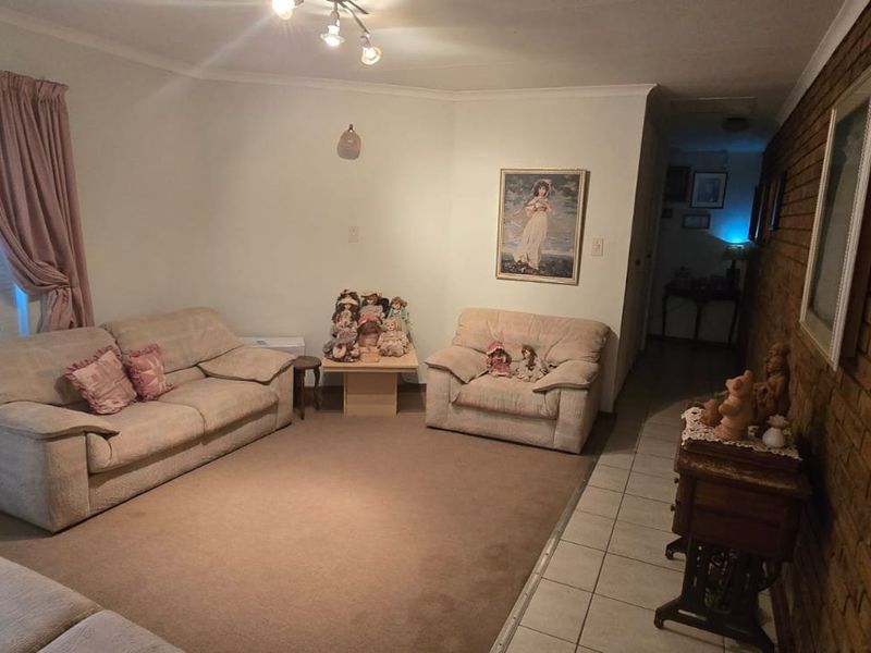 A living room featuring an exposed brick feature wall, tiled and carpeted flooring, and a sliding glass door providing natural light.