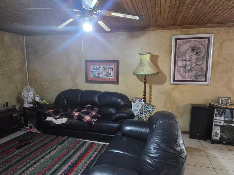 A living room featuring a timber ceiling, ceiling fan, and textured wall finishes with tiled flooring throughout.