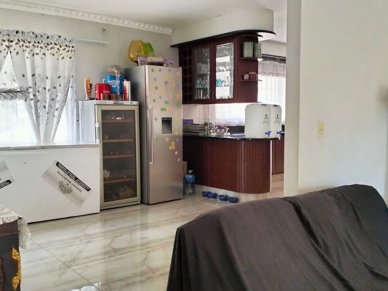 A kitchen area featuring dark wood cabinetry, granite countertops, and tiled flooring, with an open-plan layout connecting to the adjacent living space.