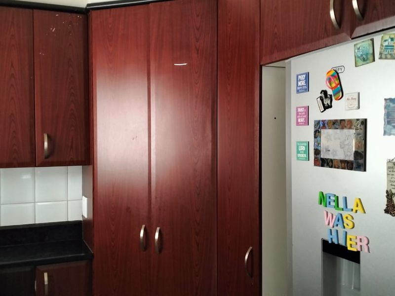 A functional kitchen featuring dark wood-finish cabinetry, a tiled backsplash, and dark laminate countertops.