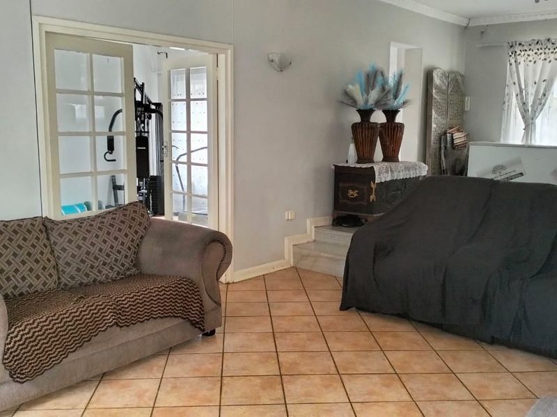 A living room featuring tiled flooring, coving, and double french doors leading to an adjacent space.
