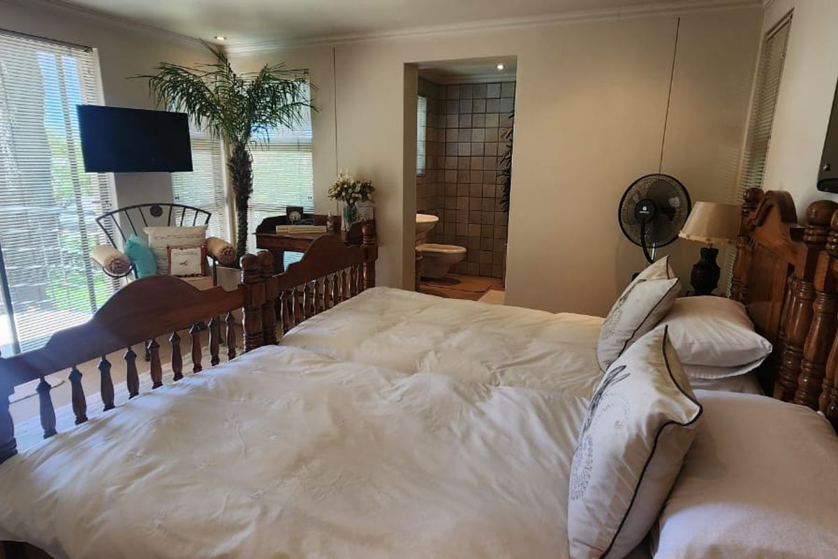 Spacious bedroom featuring sliding glass doors leading to a private balcony, with an en-suite bathroom visible through the doorway.