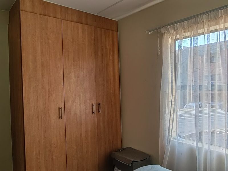 A bedroom featuring a built-in wooden wardrobe and a window with natural light.