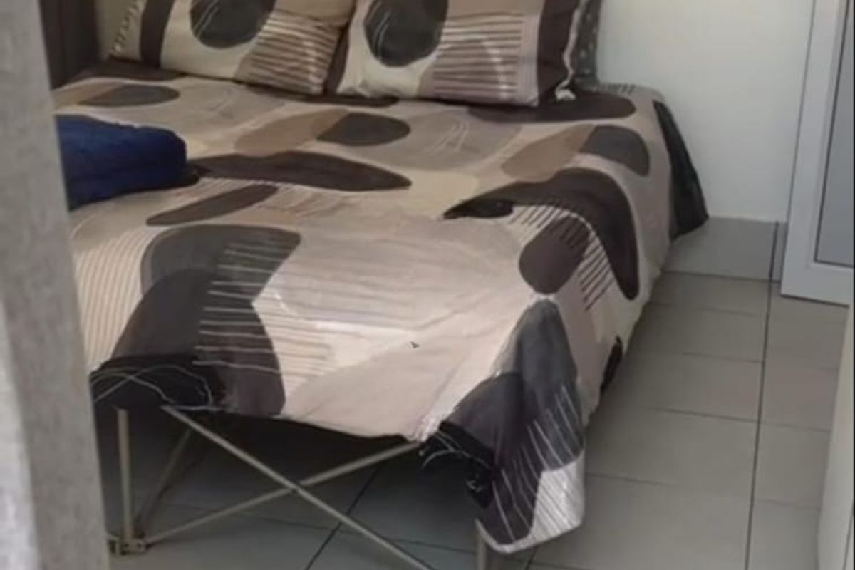 A compact bedroom featuring neutral tiled flooring and simple wall finishes, offering a functional space for rest.