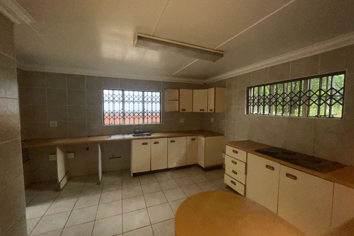 A dated kitchen featuring tiled walls and floors, built-in cabinetry, and a built-in hob, offering a functional layout ready for modernization.
