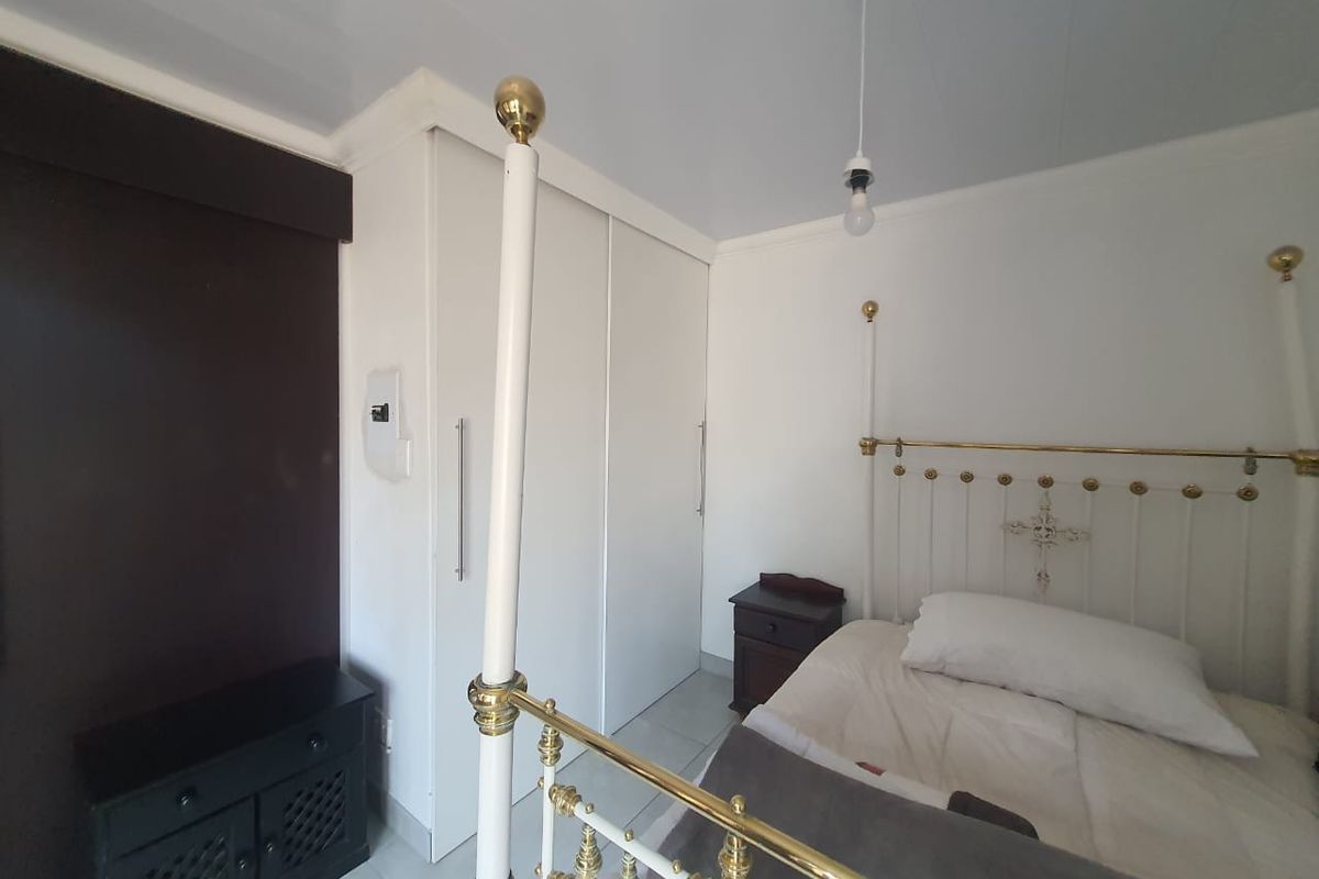 A bedroom featuring built-in floor-to-ceiling wardrobes, tiled flooring, and a neutral color palette, offering a functional and clean living space.