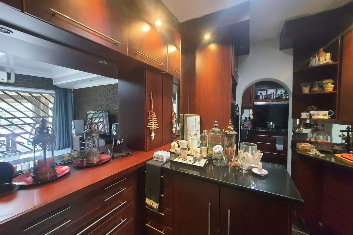 A kitchen featuring dark wood cabinetry, granite countertops, and integrated lighting, with an open-plan layout connecting to the adjacent living area.