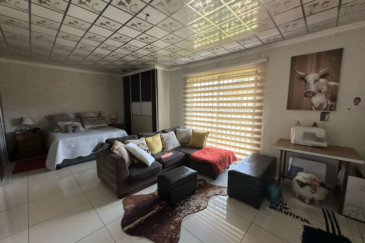 A multi-functional bedroom space featuring large format floor tiles, built-in sliding door wardrobes, and a window fitted with modern zebra blinds.