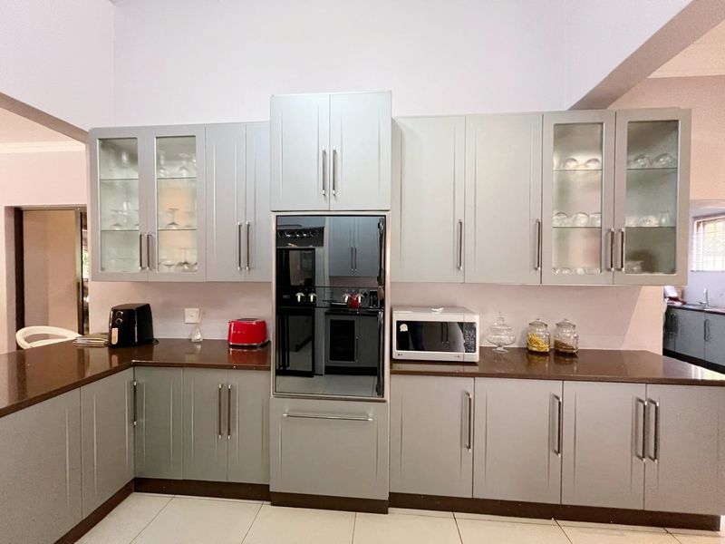 A modern kitchen featuring light grey cabinetry, dark stone countertops, and a built-in oven, offering a clean and functional workspace.