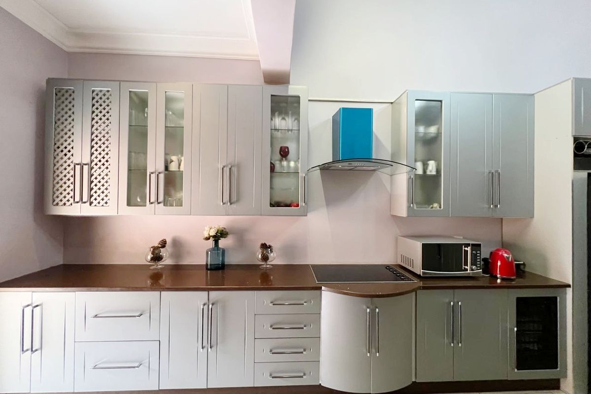 Modern kitchen featuring grey cabinetry, dark countertops, a built-in induction hob, and a stainless steel extractor fan.
