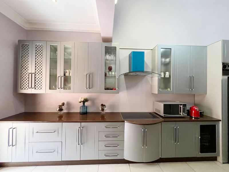 Modern kitchen featuring grey cabinetry, dark countertops, a built-in induction hob, and a stainless steel extractor fan.