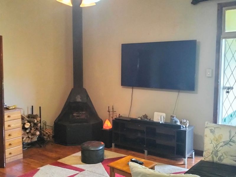 A cozy living room featuring a prominent freestanding fireplace, hardwood flooring, and a glass-paneled door leading to an outdoor area.