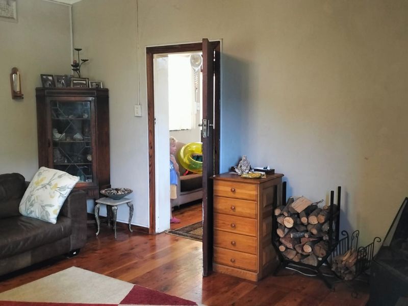 A living room featuring original hardwood flooring and a built-in freestanding fireplace, providing a cozy atmosphere with direct access to adjacent rooms.