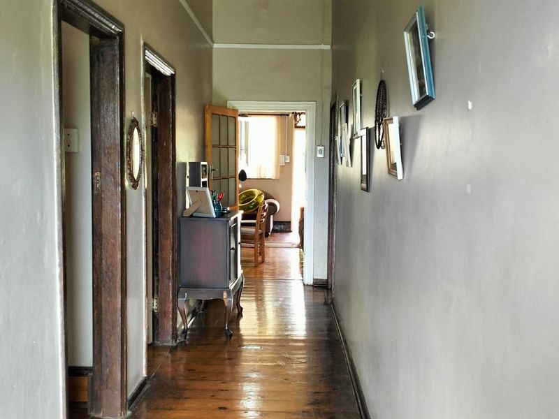 A traditional hallway featuring polished hardwood flooring and timber door frames, connecting various rooms throughout the home.