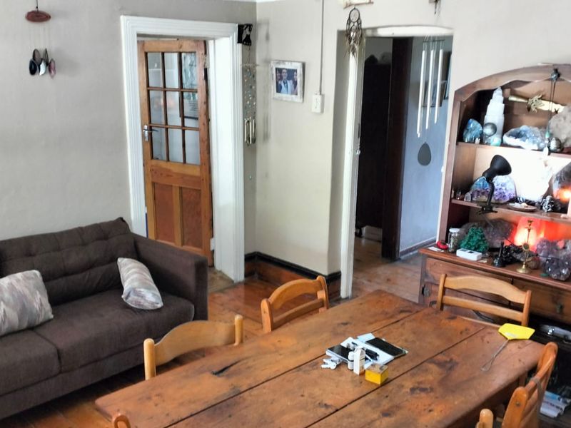 A living area featuring timber flooring, a classic timber door with glass panes, and an open archway leading to adjacent rooms.