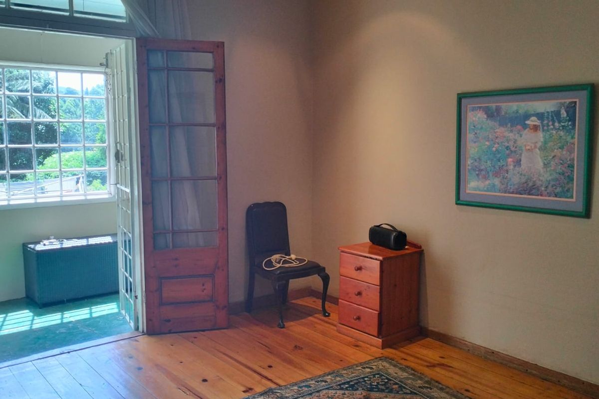 A bedroom featuring warm timber flooring and a classic timber-framed glass door providing access to an outdoor area.