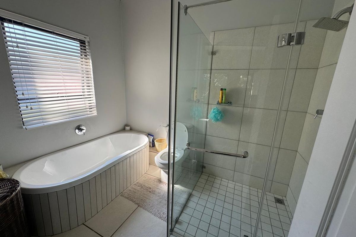 Modern bathroom featuring a freestanding bathtub, a spacious glass-enclosed shower with a rain shower head, and neutral floor-to-ceiling tiling.