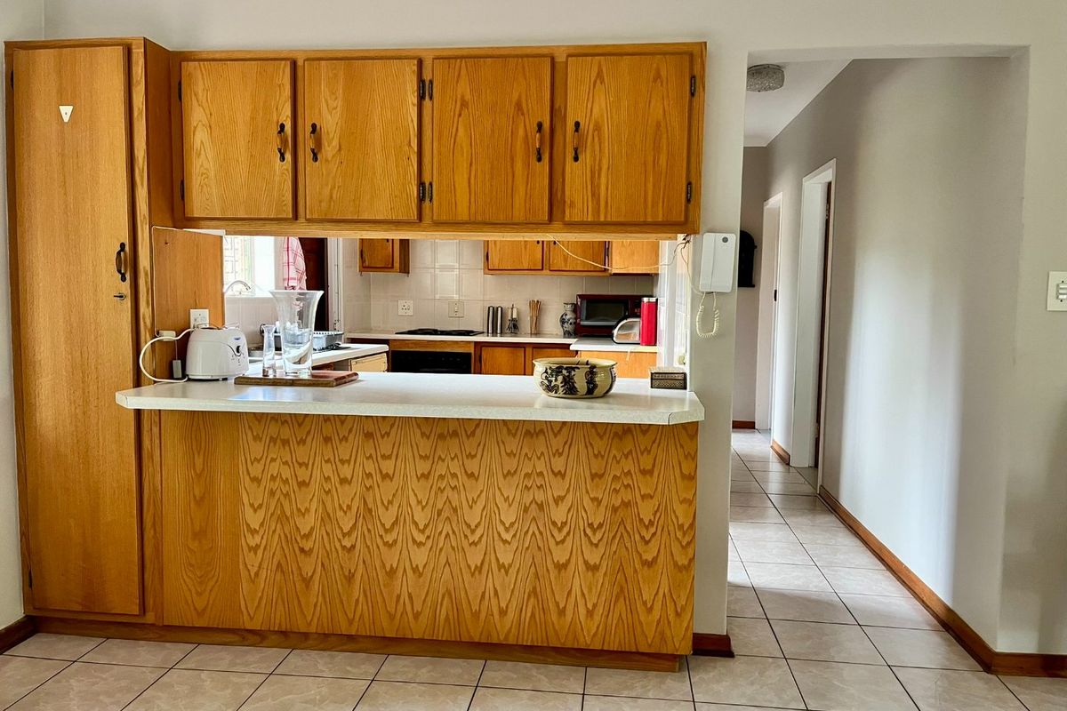 A functional kitchen featuring traditional wood cabinetry, a breakfast bar counter, and tiled flooring, providing a practical layout for daily meal preparation.