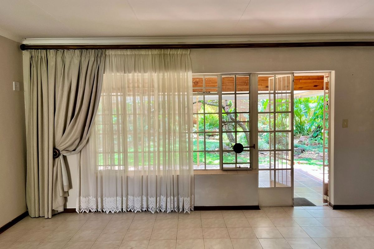 Spacious living area featuring neutral tiled flooring and large steel-framed windows and doors providing direct access to the garden.