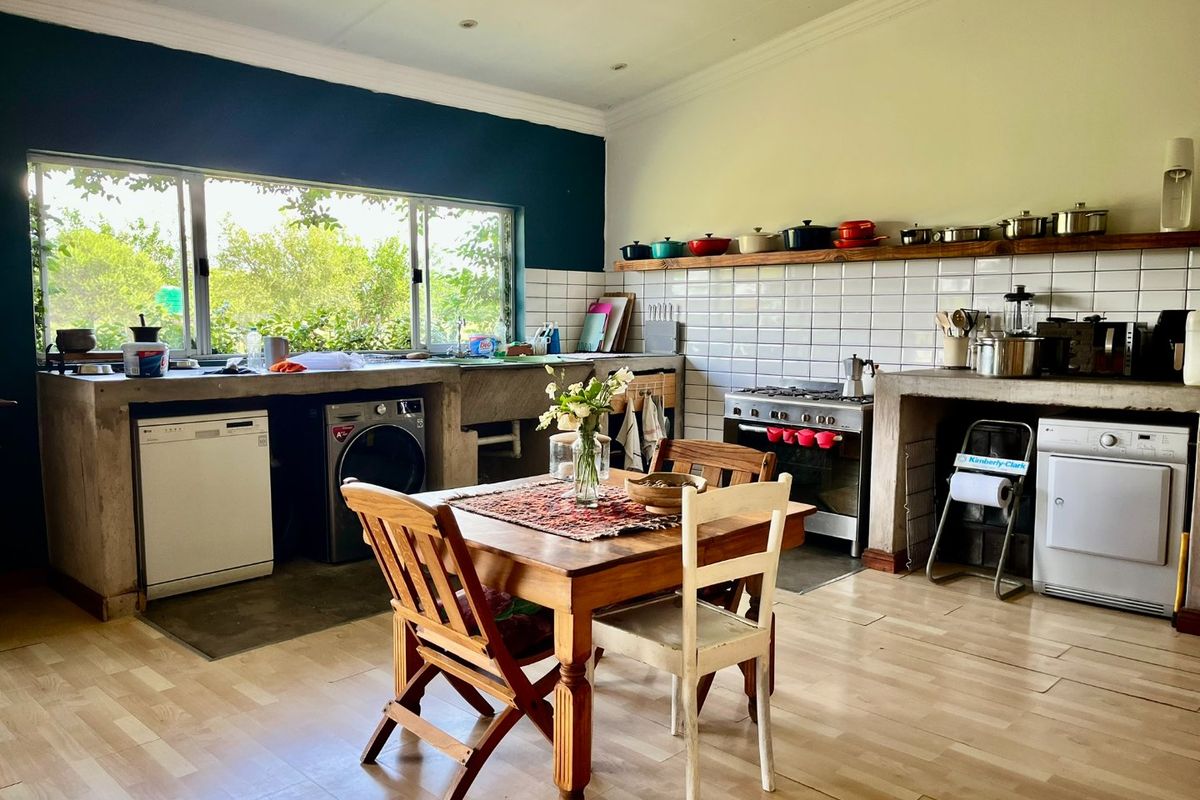 Spacious farmhouse kitchen featuring custom concrete countertops, integrated appliance spaces, white subway tile backsplash, and a dedicated dining area with garden views.