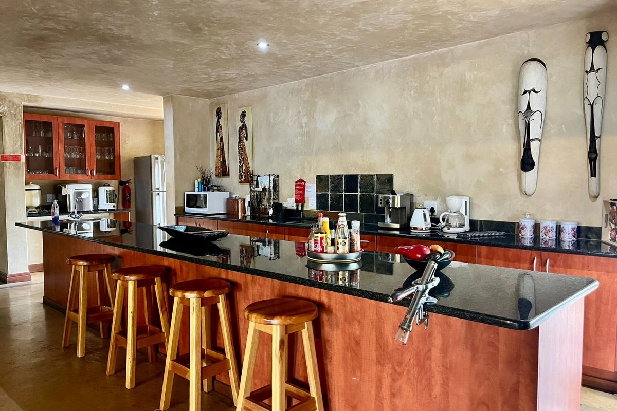 Spacious kitchen featuring a large granite-topped breakfast bar, wooden cabinetry, and recessed ceiling lighting.