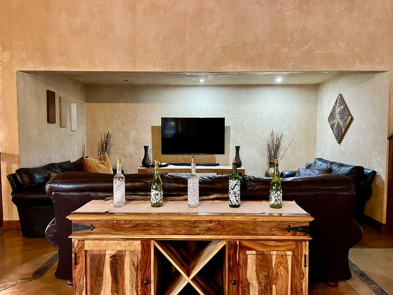 A spacious living room featuring a recessed wall area for a television, textured wall finishes, and recessed ceiling lighting.