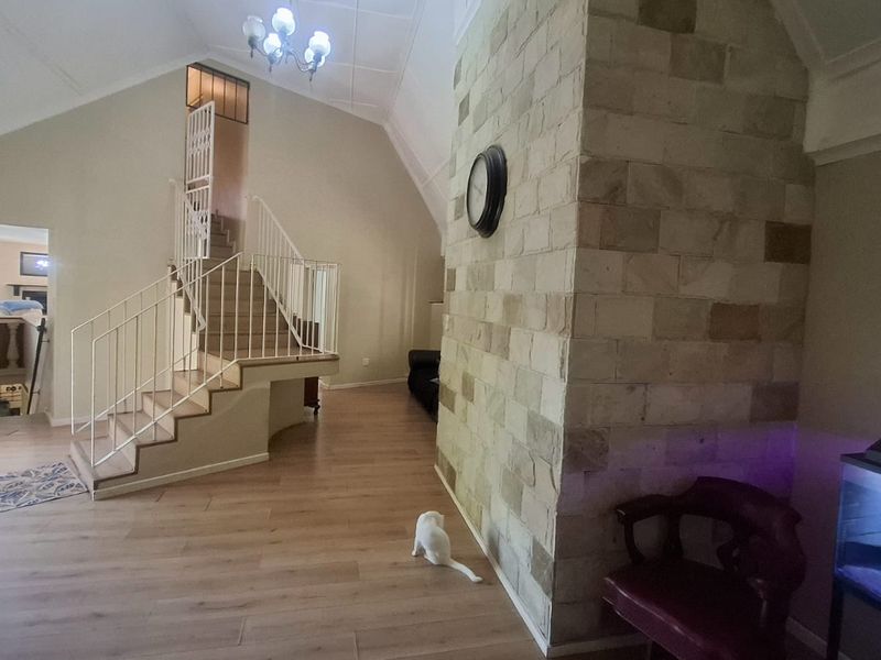 Spacious living area featuring a prominent stone fireplace, vaulted ceilings, and a central staircase with metal balustrades.