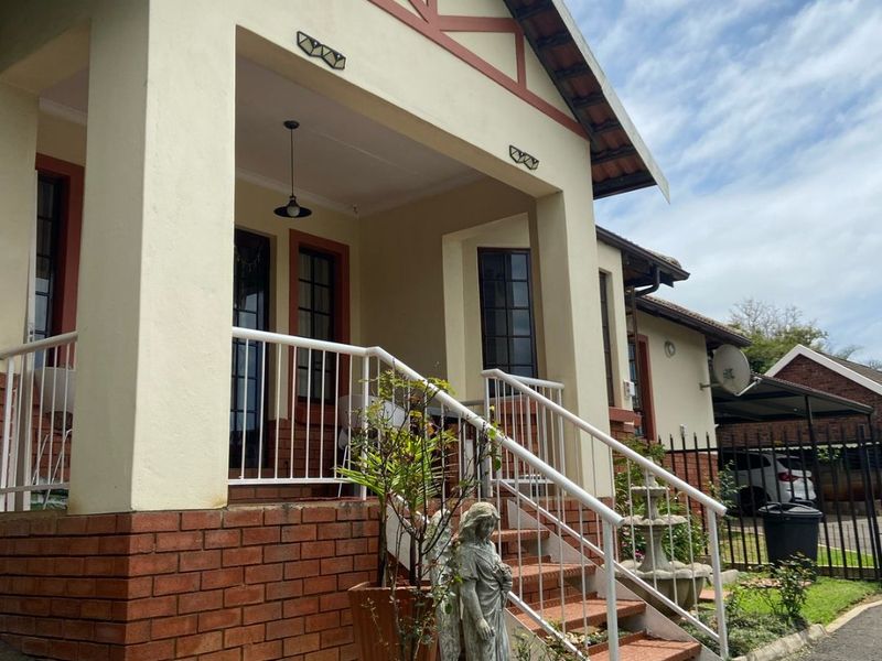 Front elevation of a townhouse featuring a covered porch, brick base detailing, and metal railings leading to the entrance.