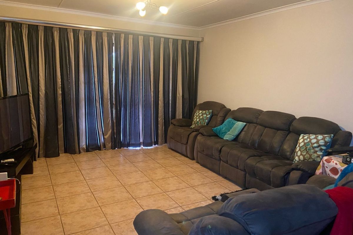 A living room featuring tiled flooring and ceiling coving, providing a functional space with direct access to an outdoor area via sliding doors.